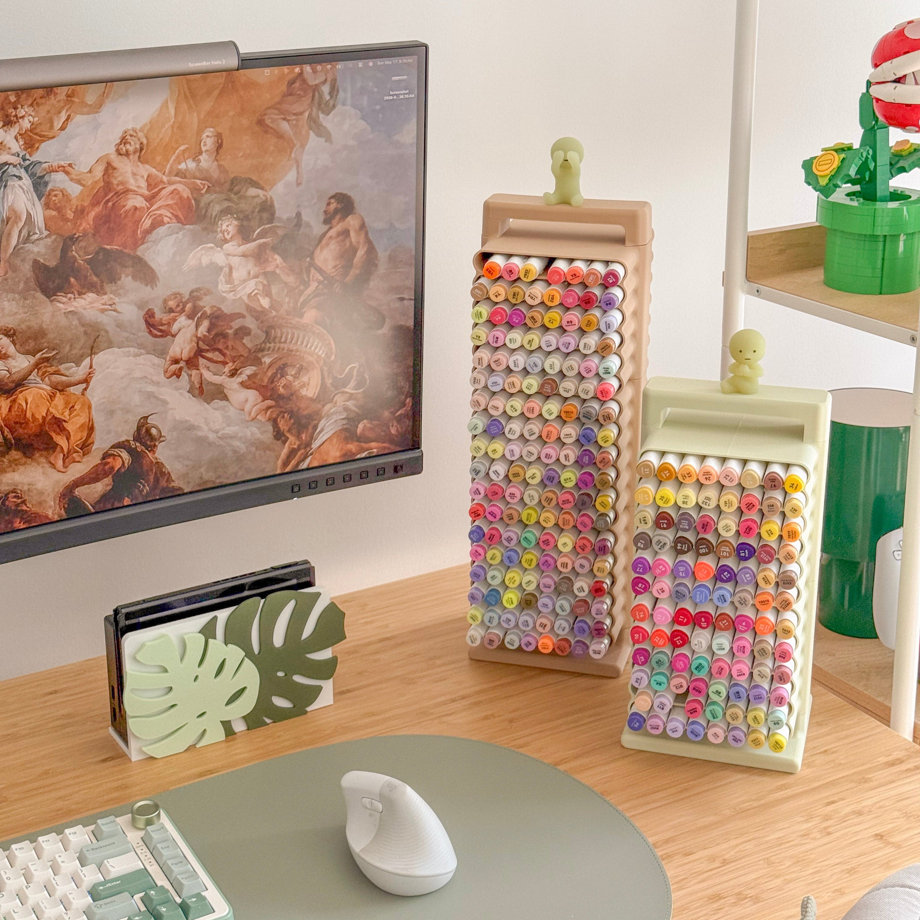 Colorful markers on a desk with a computer and decorative items.